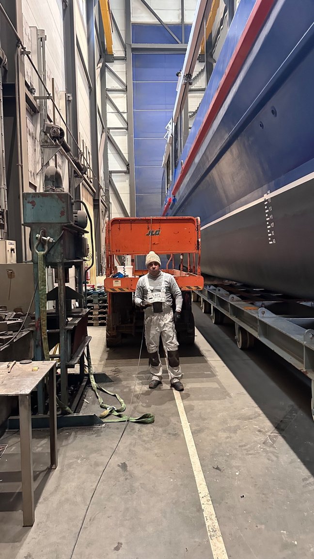 LCW worker with a large composite hull component in a production hall
