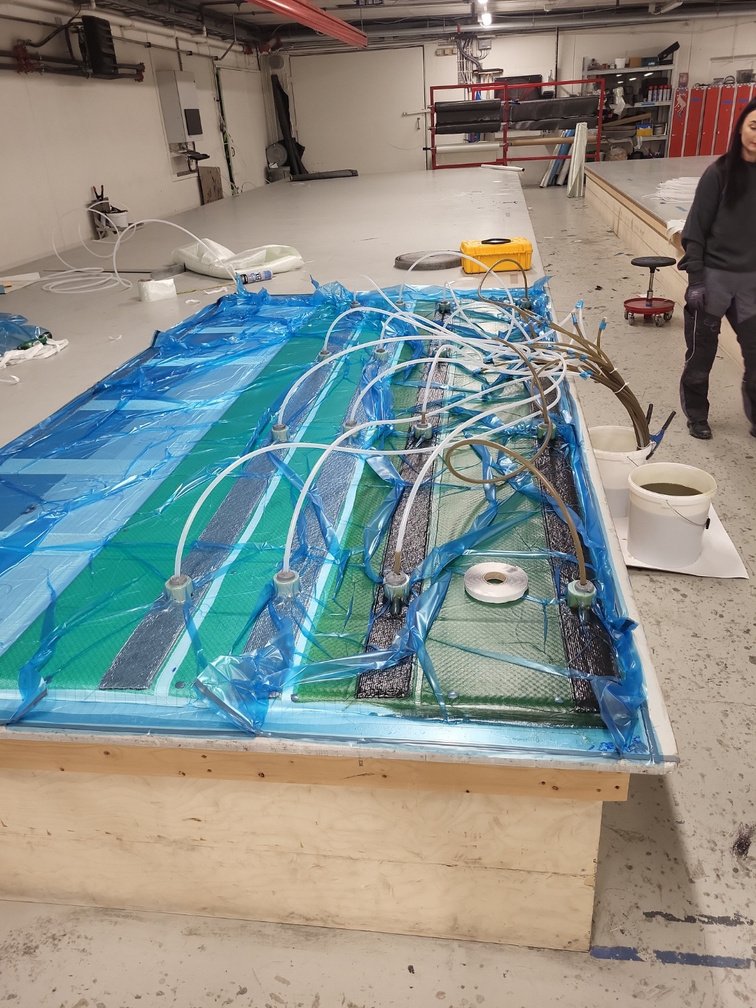 Vacuum infusion setup with resin feed lines routed across a large composite part